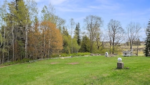 A grassy field with a small white building and a satellite dish. - Herregårdshuset AS (Ullensaker)