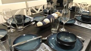 A dining table set with blue plates, silverware, and clear glasses.