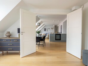 An open door leading to a dining area with a table, chairs, and a vase.