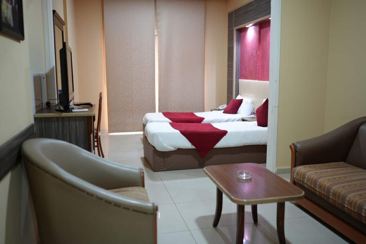 Ein Hotelzimmer mit Bett, zwei Stühlen, einem Tisch und einem Fernseher.