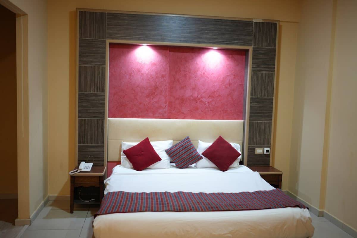 Ein Hotelzimmer mit einem großen Bett, zwei Nachttischen und einer roten Akzentwand.