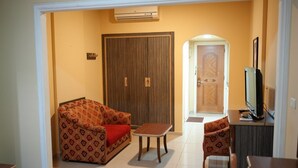 A living room with a sofa, a small table, a TV, and a door leading to another room. - Elyseeresidence Hotel  (Beirut)