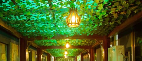 A corridor with a green artificial grass floor, a hanging light fixture, and air conditioning units on the walls.