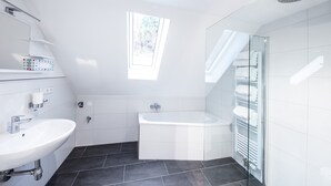 Ein modernes Badezimmer mit einem weißen Waschbecken, einer Badewanne und einer Duschkabine aus Glas.