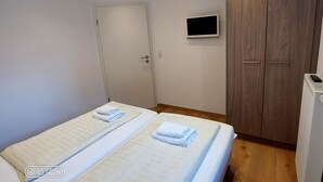 Ein Schlafzimmer mit einem Bett, einem Kleiderschrank, einem Fernseher und einer Heizung.