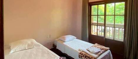 A room with two single beds, a ceiling fan, and a window with curtains.