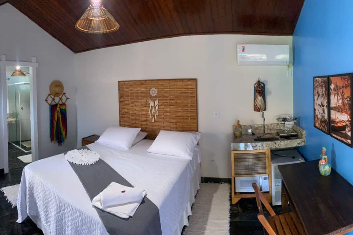 Ein Schlafzimmer mit Bett, Schreibtisch, Stuhl, Schminktisch mit Spiegel und Bildern an der Wand.