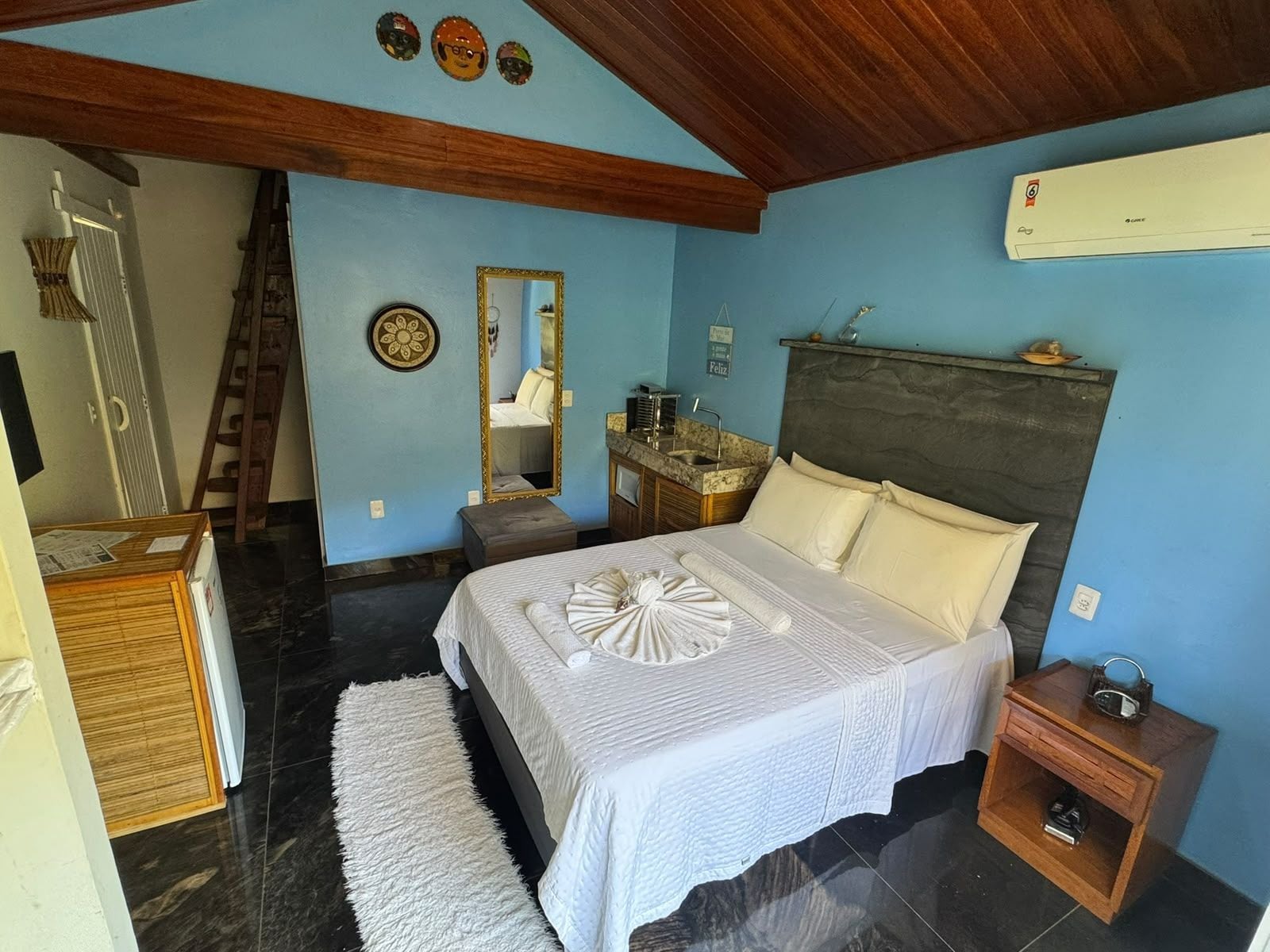 A bedroom with a bed, bedside table, and a mirror.