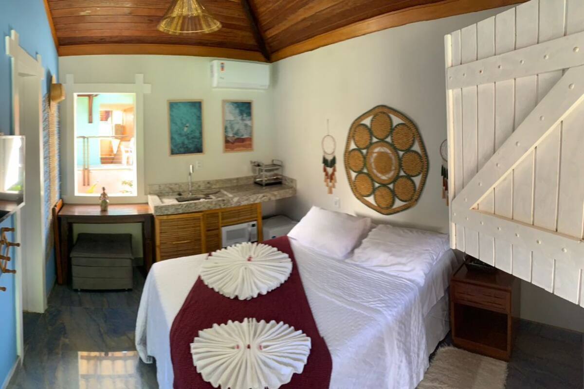 Ein Zimmer mit einem Bett, einem Schreibtisch und einem durchgehenden Türspalt sichtbaren Badezimmer.