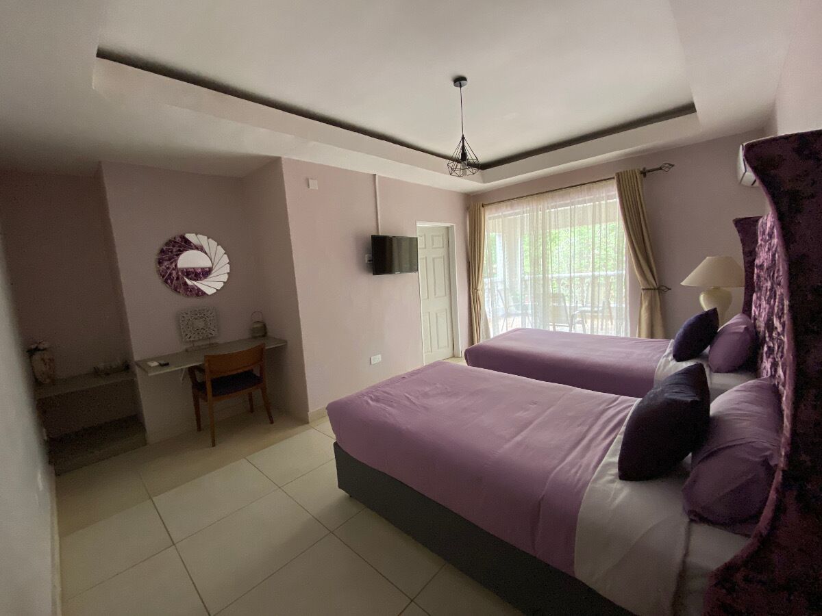 A bedroom with two beds, a desk, and a TV.