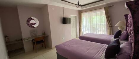 A bedroom with two beds, a desk, and a TV.
