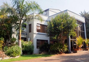 A modern building with a flat roof, large windows, and a paved entrance area.