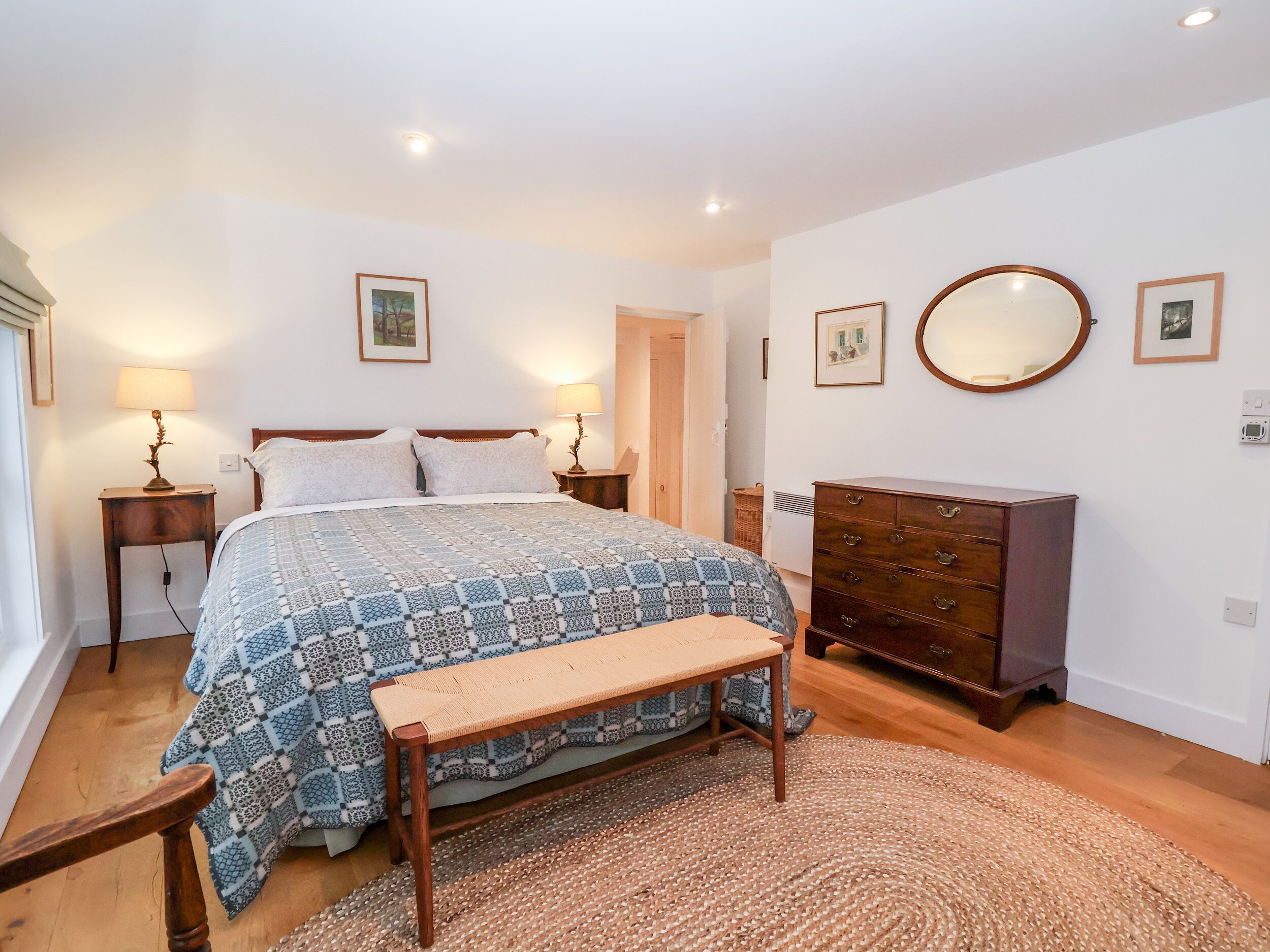 Une chambre à coucher comprenant un lit, des tables de chevet, une commode, un banc et un tapis.