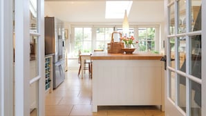 Una cocina amplia con una isla central, refrigerador y un comedor con sillas.
