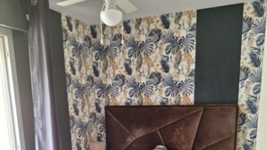 Un dormitorio con cama, ventilador de techo y papel tapiz estampado.
