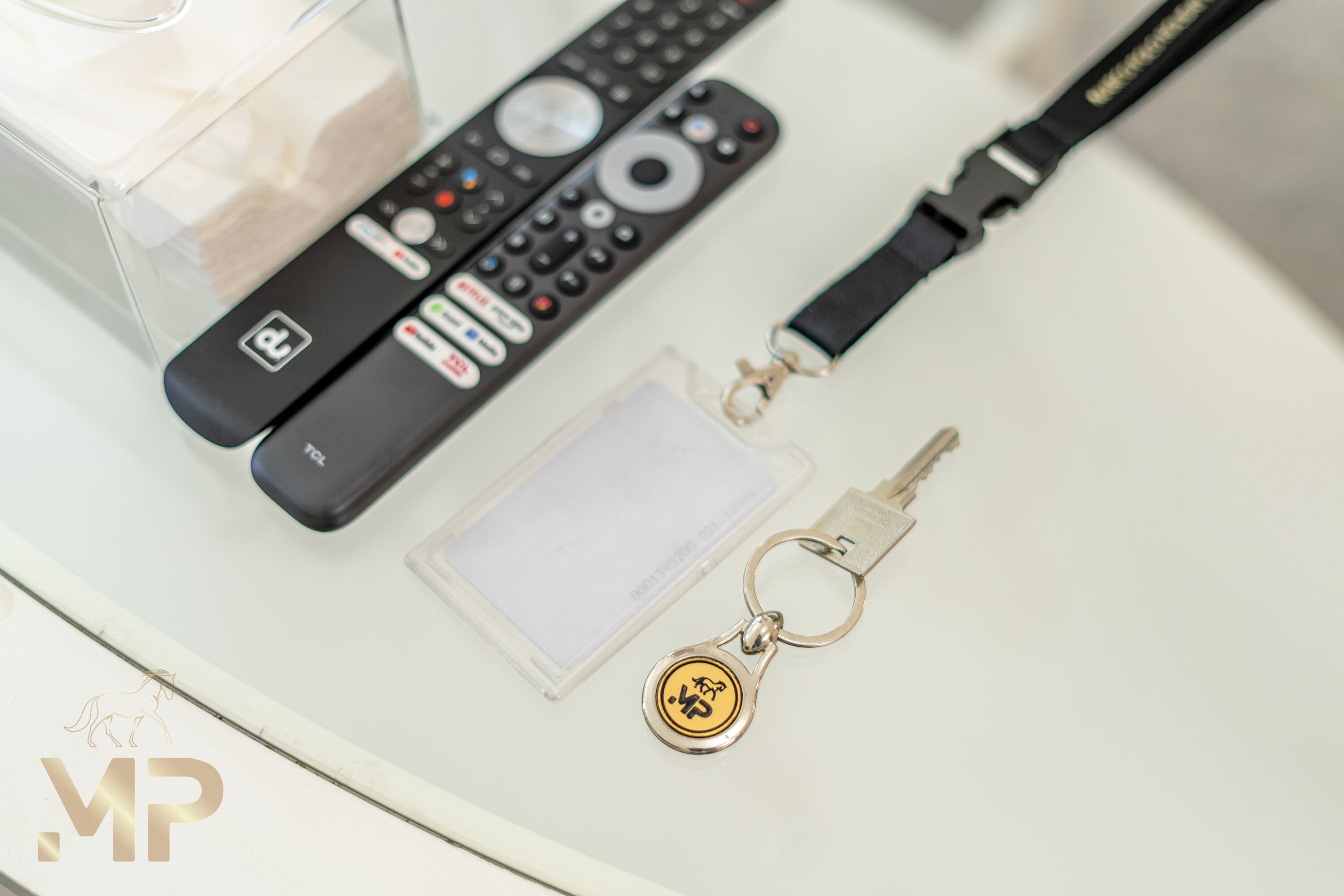 Une télécommande, un porte-clés et une clé, le tout posé sur une surface blanche.