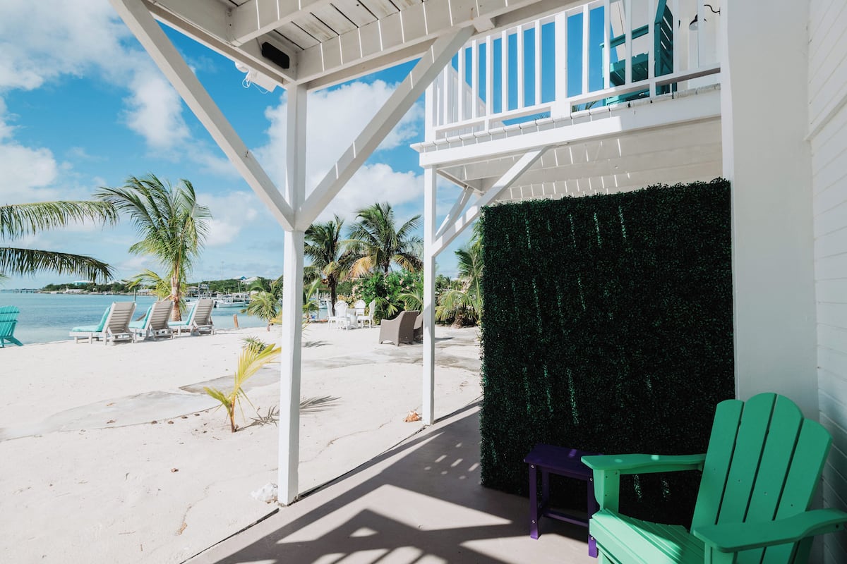 A beachside patio with white railings, a green chair, and a small table.