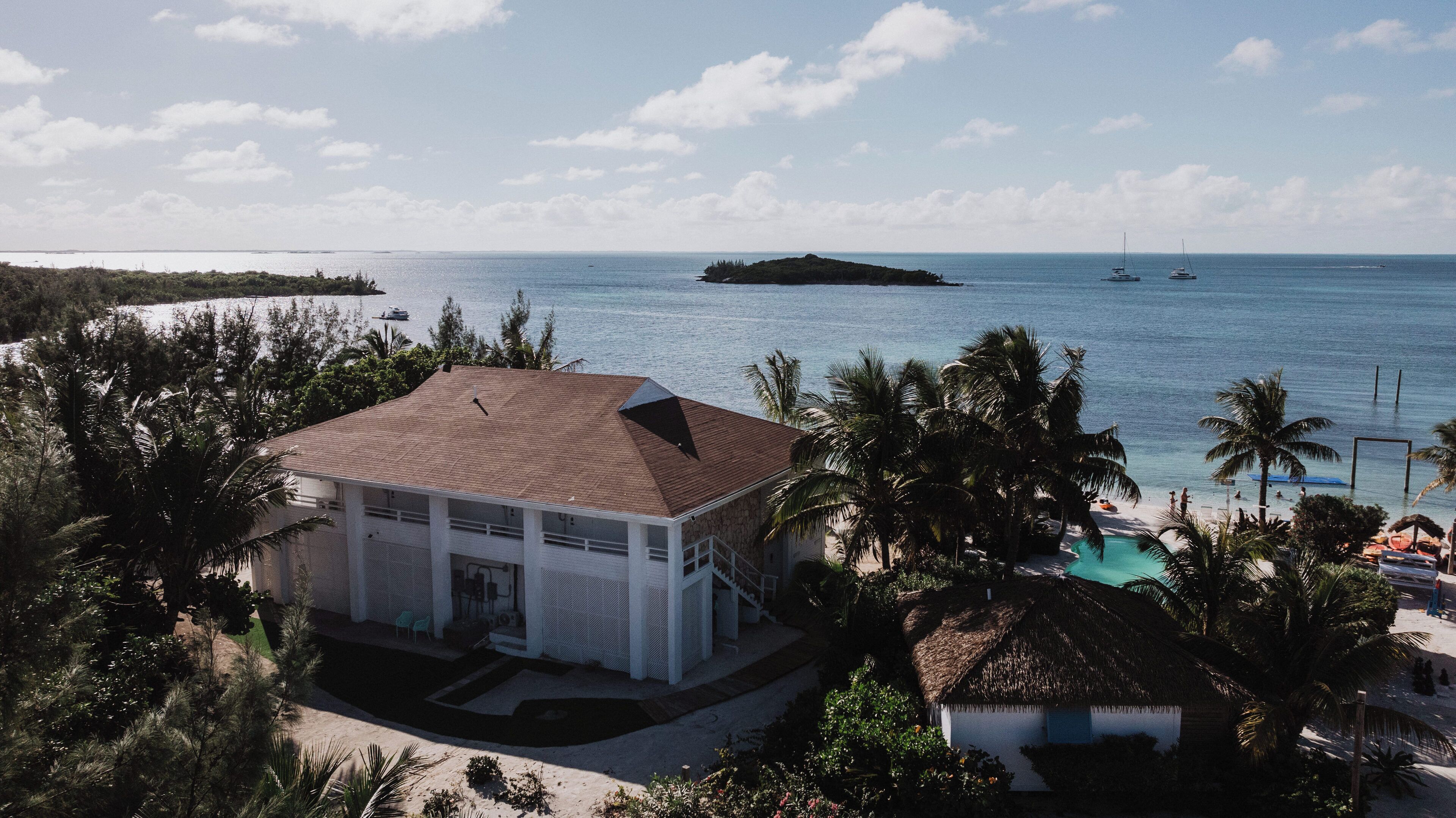 A beachfront property with a white building, a swimming pool, and palm trees.