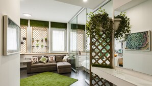 Un salon moderne avec un canapé marron, un tapis vert et des plantes en pot.