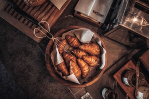 Un plateau en bois avec des croissants, une paire de ciseaux et une serviette en tissu.