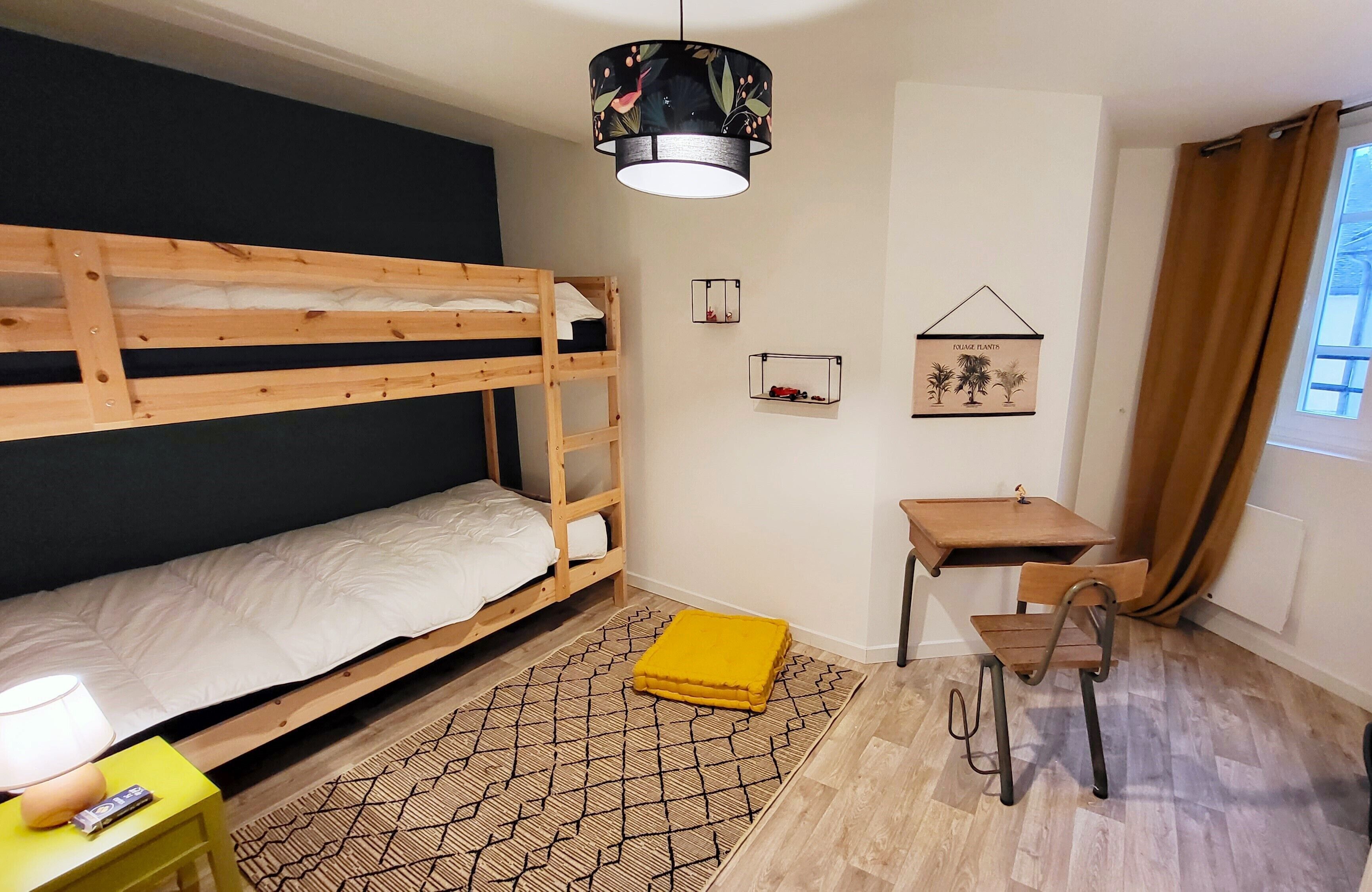 Una habitación con una cama individual, un escritorio, una silla, una lámpara y una planta colgante.