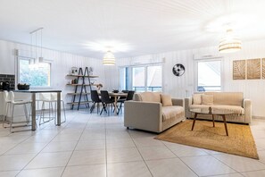 A modern living room with a sofa, coffee table, dining area, and kitchen.