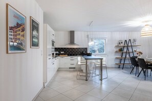 Une cuisine moderne avec des meubles blancs, un plan de travail noir et un coin repas comprenant une table et des chaises.