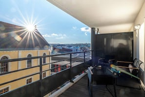 A balcony with a view of buildings, a table, and two chairs.