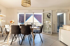 A modern dining area with a table and chairs, a clear glass door, and a view of a building outside.