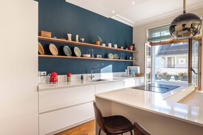 A modern kitchen with white cabinetry, a central island, and a blue accent wall.