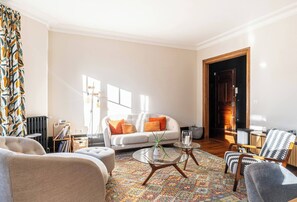 A living room with a sofa, armchairs, a coffee table, and a patterned rug.