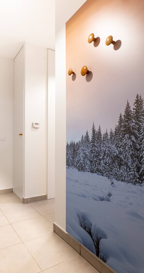A hallway with a wall-mounted thermostat, a door, and a large wall mural of a snowy forest scene.