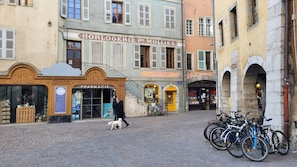 A cobblestone street with historic buildings, a pharmacy, and bicycles parked.