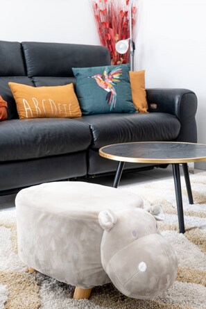 Ein Wohnzimmer mit einer Couch, einem runden Couchtisch und einem Plüschtier.