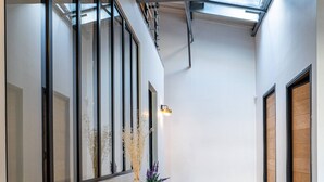 A hallway with a wooden floor, a wooden console table, a vase with dried plants, and a door with a wooden frame.