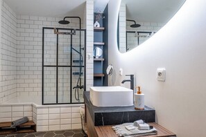 A modern bathroom with a glass shower enclosure, a white sink, and a mirror.