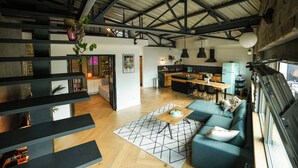 A spacious living area with a high ceiling, a dining area, and a kitchen.