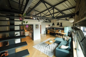 A spacious living area with a high ceiling, a dining area, and a kitchen.