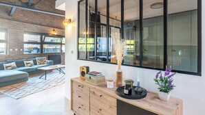 A modern living room with a sofa, a wooden console table, and a large window with a view of the outside.