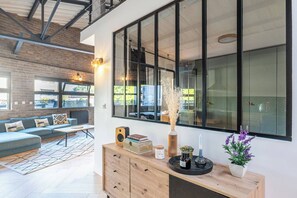 A modern living room with a sofa, a wooden console table, and a large window with a view of the outside.