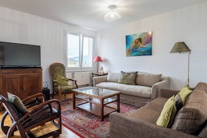 A living room with a television, sofa, armchair, coffee table, and a painting on the wall.