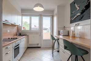 A kitchen with white cabinets, a wooden countertop, a stove, a microwave, and a green chair.