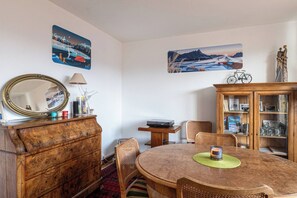 Zona pranzo con tavolo in legno, sedie, uno specchio, un armadio e due quadri appesi al muro.