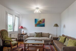 Un soggiorno con divano, poltrona, tavolino e un'opera d'arte appesa al muro.