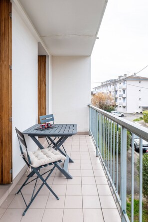 Varanda com mesa e cadeiras, vista para uma área residencial e corrimão.