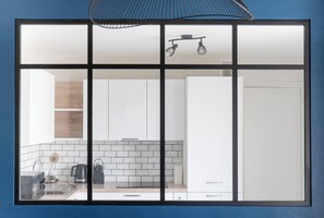 A modern kitchen with white cabinets, a tiled backsplash, and a hanging light fixture.