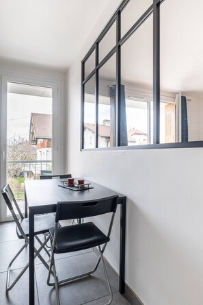 Quarto com uma mesa de jantar, cadeiras, uma janela e vista para edifícios.