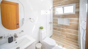 A modern bathroom with a wooden door, a large mirror, a sink, a toilet, and a shower area. - First Class 4br King Size Villa In Sosua Town! (Sosúa)
