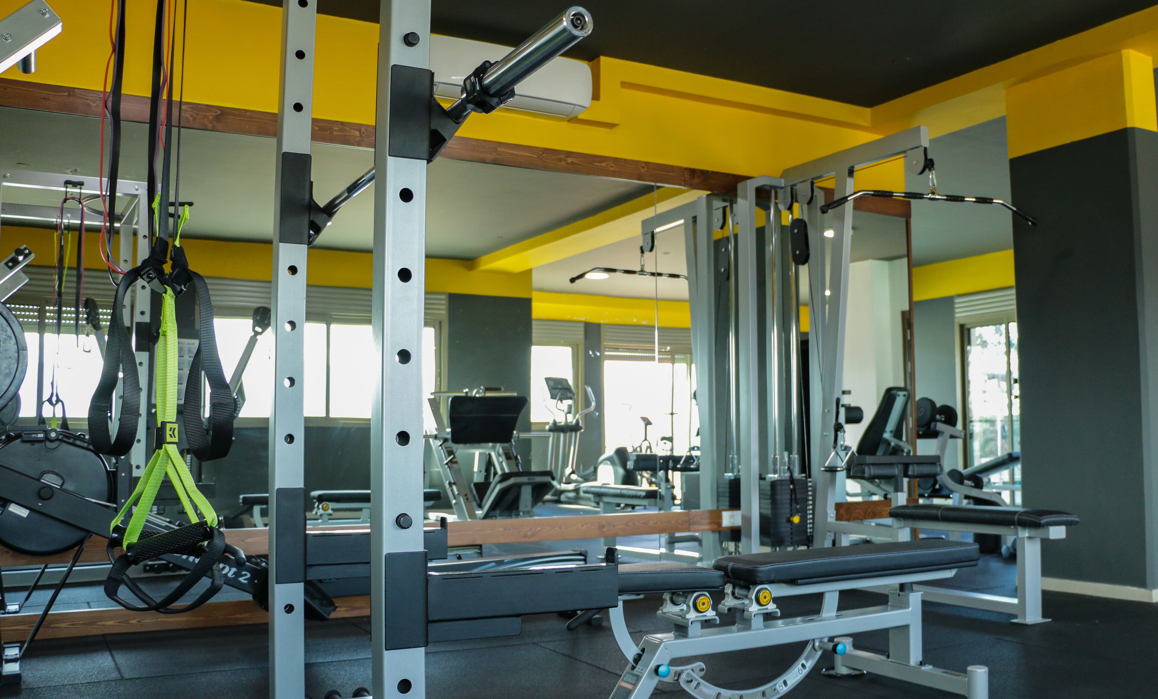 Ein Fitnessraum mit Trainingsgeräten, Spiegeln und einer Bank.