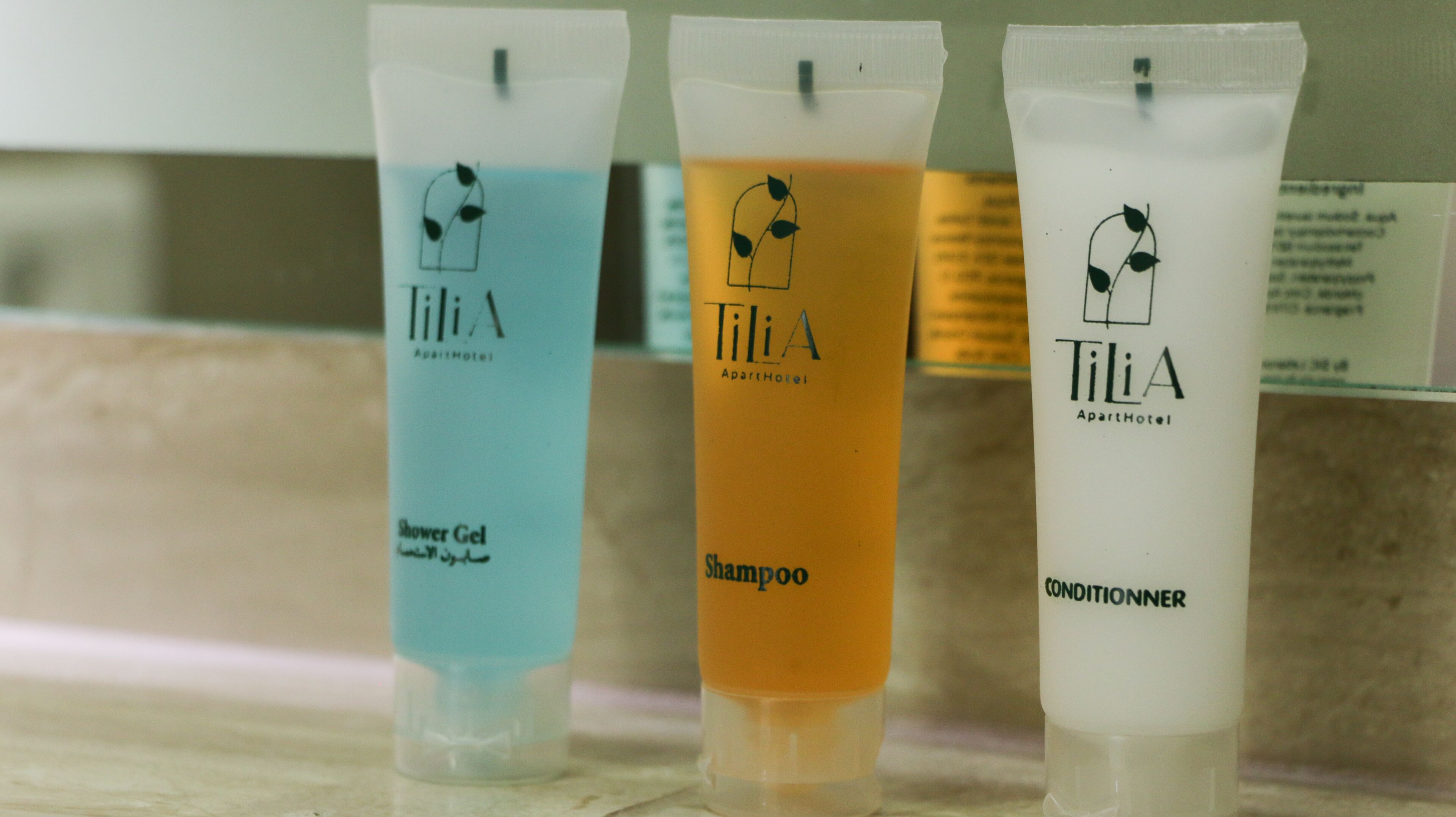 Three Tilia A products: a blue shower gel, an orange shampoo, and a white conditioner.